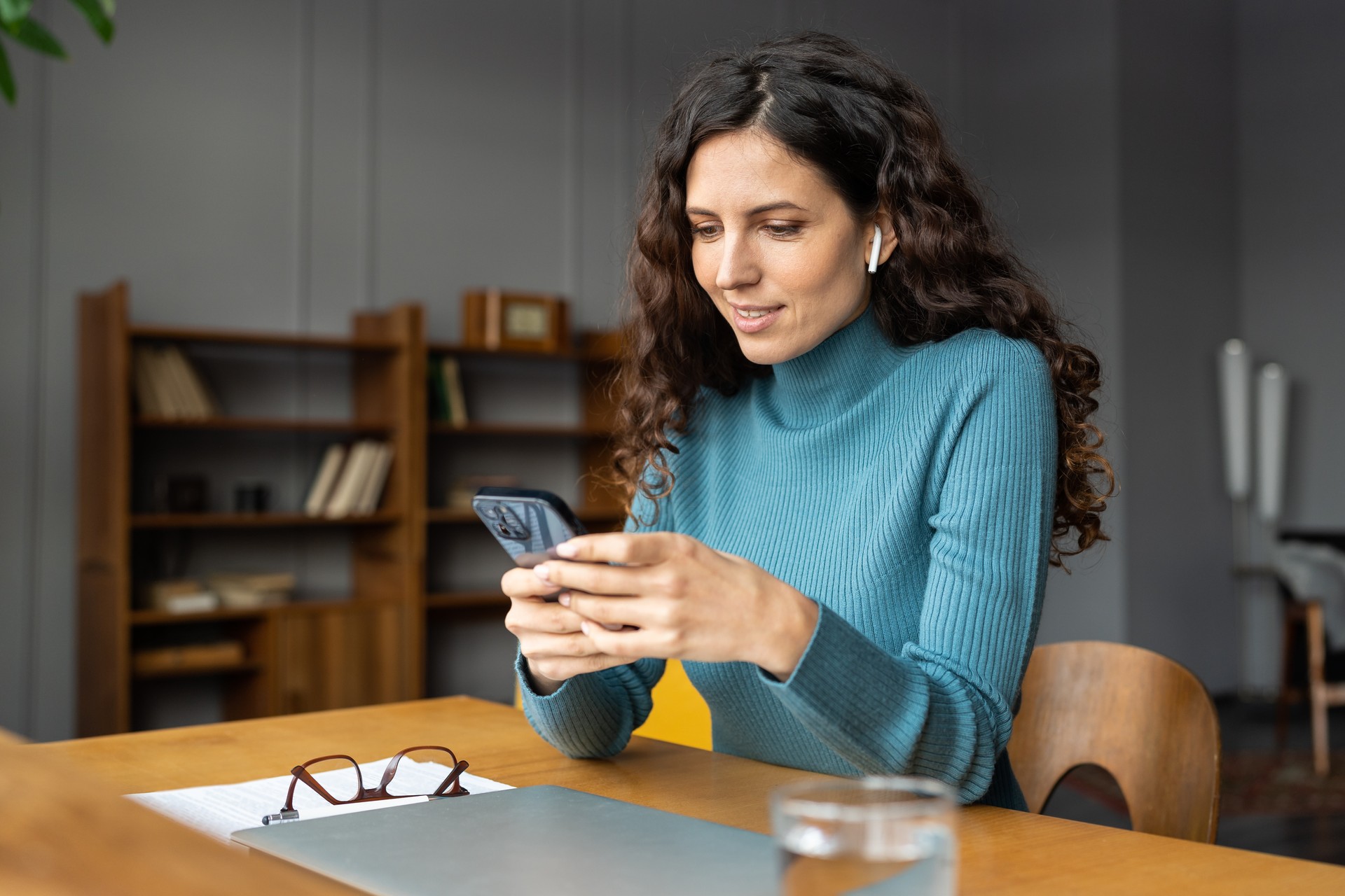 Smiling businesswoman distracted from work on notification from social media in mobile phone device